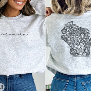 May include: A gray sweatshirt with the text "wisconsin" and a heart on the front. The back of the sweatshirt features a black and white outline of the state of Wisconsin filled with a floral pattern.