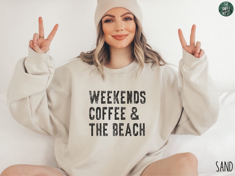 May include: A beige sweatshirt with the text "Weekends Coffee & The Beach" in black distressed lettering.