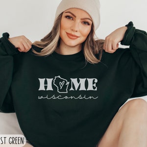 May include: A dark green sweatshirt with the text "HOME" in white with a white outline of the state of Wisconsin with a heart inside. The text "wisconsin" is written in cursive below the word "HOME". The sweatshirt is available in 2XL and is forest green.