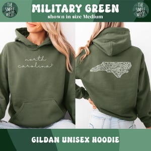 Pu&ograve; includere: Felpa con cappuccio unisex Gildan verde militare. La parte anteriore presenta la scritta "north carolina" in bianco. Il retro mostra un contorno bianco e dettagliato della Carolina del Nord. La felpa con cappuccio &egrave; mostrata in taglia Medium.