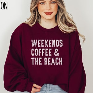 May include: A maroon sweatshirt with the text "Weekends Coffee & The Beach" in white distressed lettering.