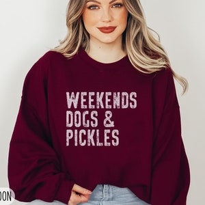 Op de afbeelding: Een maroon sweatshirt met de tekst "Weekends Dogs & Pickles" in wit. Het sweatshirt is een relaxed fit en heeft een ronde hals.