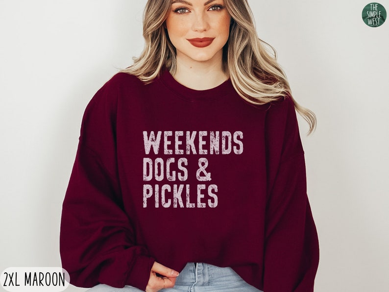 Op de afbeelding: Een maroon sweatshirt met de tekst "Weekends Dogs & Pickles" in wit. Het sweatshirt is een relaxed fit en heeft een ronde hals.