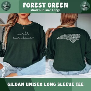 May include: Forest green Gildan unisex long sleeve tee. The front features the text "north carolina" in white script. The back displays a white decorative outline of North Carolina. The shirt is shown in size Large.