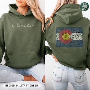 May include: A medium military green hoodie with the word "colorado" in white script on the front. The back features a detailed graphic of the Colorado state flag. The Simple West logo is in the upper right corner.