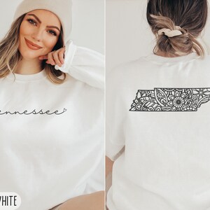 May include: White sweatshirt with the word "Tennessee" and a heart on the front. The back of the sweatshirt features a black and white mandala design of the state of Tennessee.