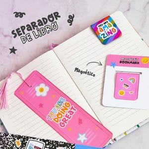 May include: An assortment of decorative bookmarks and a magnetic bookmark are shown on an open notebook. The bookmarks feature diverse designs, including a pink bookmark with the text "YOU ARE DOING GREAT" and a black and white bookmark with the text "YOU GOT THIS!".