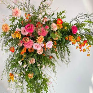 Composizione autunnale con arco nuziale con fiori arancioni, rosa e rosa chiaro e verde