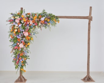 Composizioni floreali di fiori selvatici per arco nuziale nelle tonalità dell'arancione, del rosa, del giallo e del viola.