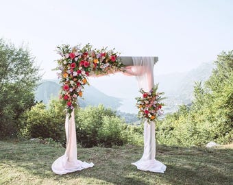 Arco nuziale rustico con fiori selvatici rosa acceso, viola, azzurro e rosa pallido.