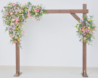 Composizioni floreali per arco nuziale a tema fiori selvatici nei colori rosa, malva, blu e giallo.