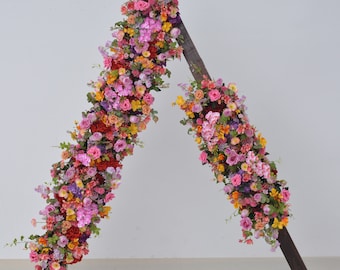 Arco nuziale con fiori rosa acceso, viola e arancioni per la cerimonia di nozze.