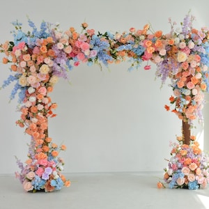 Composizione floreale per arco nuziale color pastello con pesca tenue, rosa cipria, azzurro e lavanda
