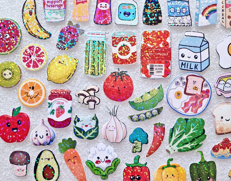 May include: A collection of colorful, cartoon-style food stickers, including fruits, vegetables, and packaged goods. The stickers feature smiling faces and glitter accents, with items like a banana, lemon, tomato, milk carton, and a slice of watermelon.