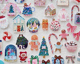 May include: A collection of colorful Christmas-themed stickers. Designs include gingerbread men, Christmas trees, sweaters, houses, bows, and snow globes. The stickers are in various shapes and sizes, with glitter and holographic accents. The overall theme is festive and cheerful.