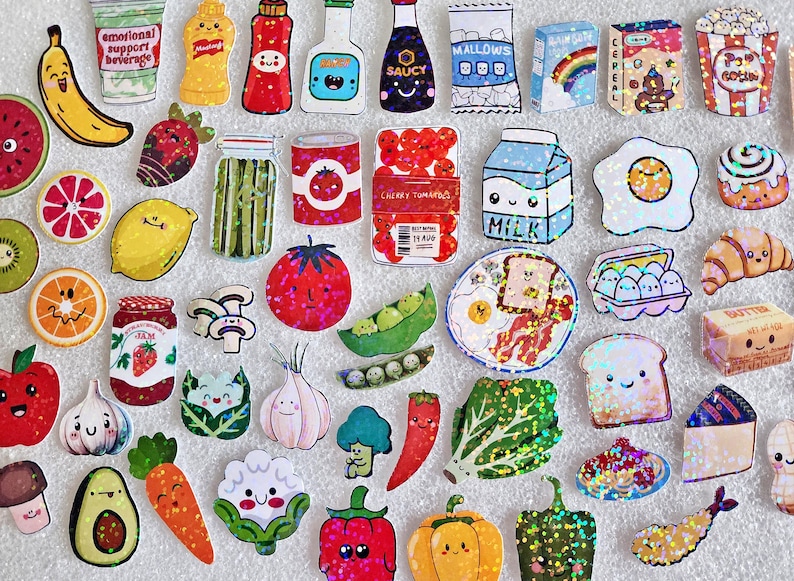 May include: A collection of colorful food-themed stickers, including fruits, vegetables, condiments, and breakfast items. The stickers feature cute, cartoon-like designs with glitter accents. Items include a banana, tomato, milk carton, and popcorn.