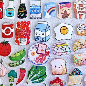 May include: A collection of colorful food-themed stickers, including a carton of milk, a fried egg, a slice of toast, and a plate of bacon and eggs. Other stickers include popcorn, cereal, and various vegetables.