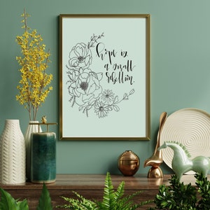 May include: A framed print with a light blue background and black line art of flowers. The text "Hope is a small rebellion." is written in black cursive.