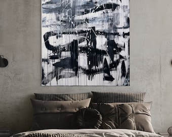 May include: A black and white abstract painting with bold brushstrokes and splatters of paint. The painting is framed and hanging on a gray wall above a bed with brown bedding.
