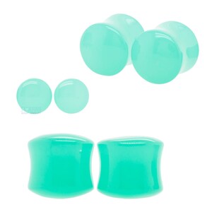 May include: Set of four turquoise acrylic ear gauges. Two are round and two are flared.