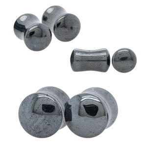 May include: A set of six hematite ear gauges in various sizes and shapes. The gauges are a dark gray color with a shiny finish.
