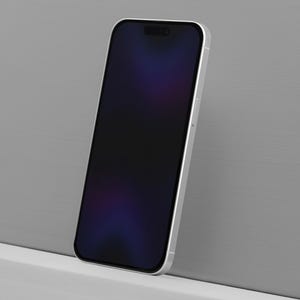 May include: A silver smartphone with a black screen, leaning against a gray wall. The phone's screen displays a dark, blurred image with hints of purple and blue. The phone has a sleek, modern design.
