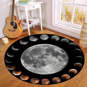 May include: A round black and white rug featuring a large full moon in the centre and a circle of smaller moons around the edge. The smaller moons are in different phases of the lunar cycle.