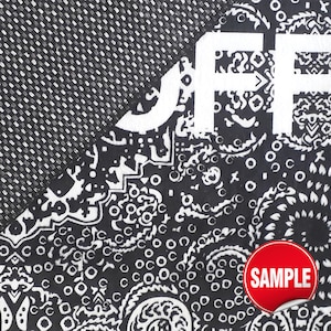 Puede incluir: Una tela en blanco y negro con un patr&oacute;n detallado de bandana de cachemira con las letras blancas JFF impresas en la parte superior. El material tiene un tejido texturizado e incluye una pegatina circular roja con el texto blanco SAMPLE.