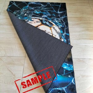 May include: A blue and black rug with a cracked glass design. The rug has a black non-slip backing. The rug is labeled "SAMPLE".