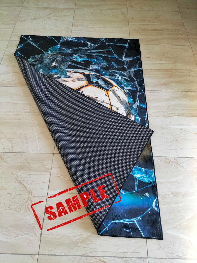 May include: A blue and black rug with a cracked glass design. The rug has a black non-slip backing. The rug is labeled "SAMPLE".