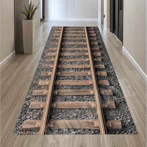 Peut inclure: Un tapis rectangulaire avec un motif de voie ferrée. Le tapis présente une représentation détaillée de traverses en bois, de rails en acier et de gravier, créant un effet 3D réaliste. Le tapis est posé sur un sol en bois dans un couloir.