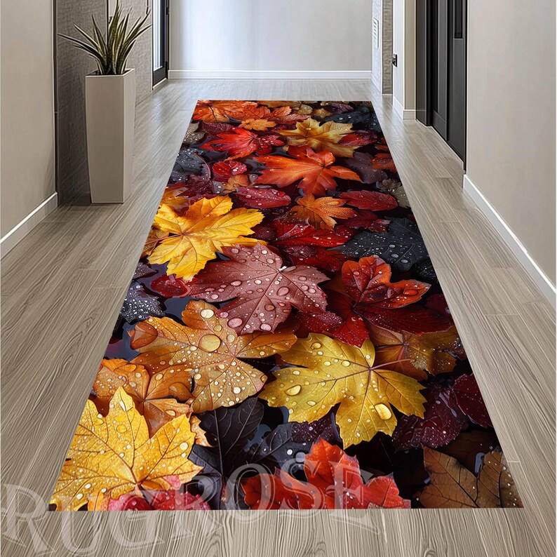 Puede incluir: Una alfombra de pasillo rectangular larga con un estampado fotogr&aacute;fico de alta definici&oacute;n de hojas de oto&ntilde;o ca&iacute;das en tonos amarillo vibrante, naranja intenso y rojo oscuro. Las hojas est&aacute;n cubiertas de gotas de agua claras.