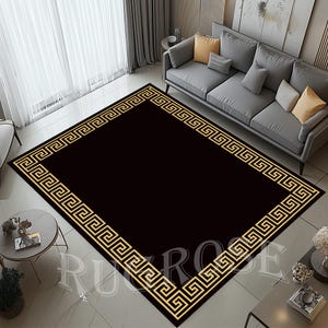 Pode incluir: Tapete preto com um design de borda de chave grega dourada. O tapete está sobre um piso de cor clara.