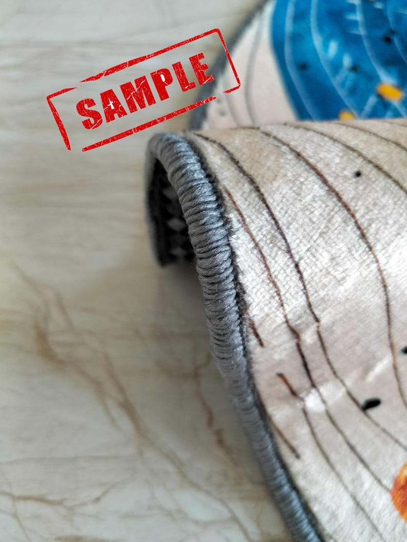 May include: Close-up of the edge of a rug with a gray border. The rug has a white background with a brown and white striped pattern.