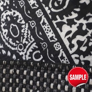 Puede incluir: Una tela en blanco y negro con un patr&oacute;n detallado de cachemira y flores con un borde tejido texturizado en la parte inferior. Una pegatina roja circular con el texto blanco SAMPLE est&aacute; colocada en la esquina inferior derecha de la imagen.