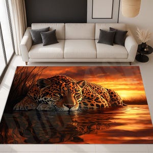 May include: A rectangular area rug featuring a jaguar resting in water, with a sunset backdrop. The rug's design includes the jaguar's spotted coat in shades of brown and black, set against a warm orange and yellow sky. The rug is placed in a living room.