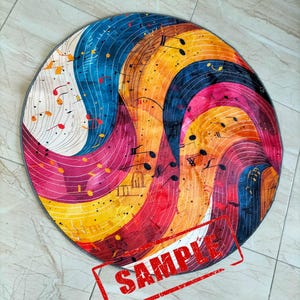 May include: A round rug with a colorful abstract design featuring musical notes and swirls of blue, yellow, red, and white. The rug has a gray border.