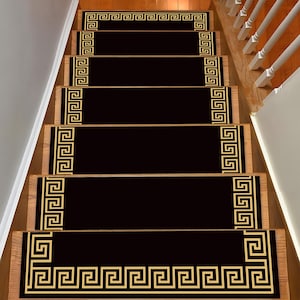 Può includere: Battiscopa per scale neri e dorati con un motivo geometrico. I battiscopa sono realizzati in un materiale morbido e resistente e sono progettati per proteggere le scale dall'usura.