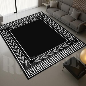 Pode incluir: Um tapete retangular preto com uma borda branca com um design de chave grega e detalhes de folhas. O tapete está colocado numa sala com um sofá cinzento e uma cadeira preta.