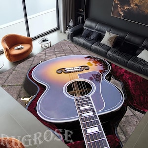 May include: A vintage acoustic guitar with a sunburst finish and a black pickguard, open in its case with a red velvet lining. The guitar is in focus, while the background is blurred.