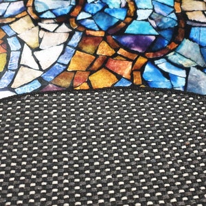May include: A close-up of a black and white patterned fabric with a colourful stained glass design. The fabric has a textured surface and is ideal for upholstery or crafts.