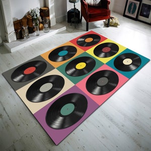 Könnte beinhalten: Ein bunter Teppich mit einem Design aus neun schwarzen Schallplatten auf weißem Hintergrund. Jede Schallplatte befindet sich auf einem quadratischen Feld in einer anderen Farbe.