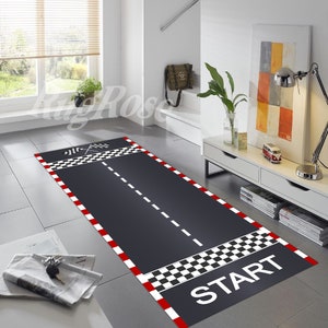 May include: A black and white checkered race track rug with red borders and a white dashed line down the center. The rug has the word "START" printed in white at the bottom.