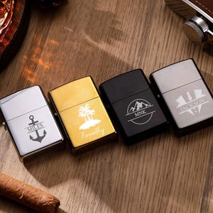 Könnte beinhalten: Vier personalisierte Feuerzeuge in Silber, Gold, Schwarz und Gunmetal. Jedes Feuerzeug hat ein einzigartiges Design: ein Anker mit "MILES", eine tropische Insel mit "Timothy", eine Berglandschaft mit "MNK" und ein Wappen mit "JACKSON".