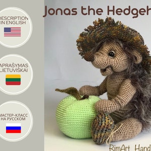 May include: A crocheted hedgehog wearing a brown and green hat sits next to a green crocheted apple. The hedgehog is brown with a light brown face and has a stitched smile. The text "Jonas the Hedgehog" is written in brown letters above the hedgehog. The text "RimArt Handmade" is written in brown letters below the hedgehog.