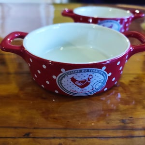 Op de afbeelding: Rode en witte keramische ramekin met een witte binnenkant en een kipontwerp. De ramekin heeft de tekst "Cuisine du Terroir" en "Savoir de Qualite" erop gedrukt.