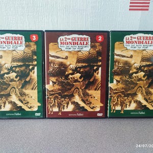 Peut inclure: Trois cassettes VHS avec des étuis verts, bruns et rouges. Chaque étui présente une photo d'une jeep militaire et de soldats. Le texte sur les cassettes indique "La 2eme Guerre Mondiale" et "Tous les faits marquants Front par front".