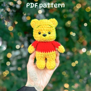 Puede incluir: Un oso de peluche tejido a ganchillo en amarillo y rojo con ojos y nariz negros. El texto "PDF pattern" es visible en la parte superior de la imagen. El oso tiene cabeza, brazos y piernas amarillos, con una camiseta roja en el torso.