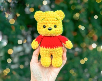 May include: A yellow and red crocheted bear plush toy with black eyes and a black nose. The text "PDF pattern" is visible at the top of the image. The bear has a yellow head, arms, and legs, with a red shirt covering its torso.