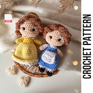 May include: Crochet pattern PDF for two amigurumi dolls. The dolls are dressed in yellow and blue dresses with white accents. The dolls have brown hair and brown eyes.